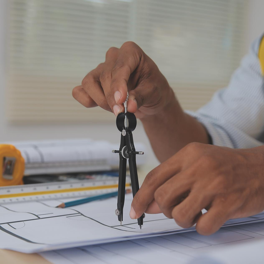 Architect drawing blueprints with a compass